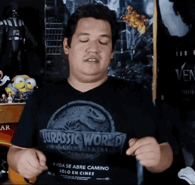 a man wearing a jurassic world t-shirt makes a funny face