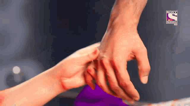 a close up of a person holding another person 's hand with a sony logo in the background