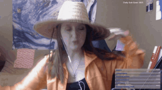 a woman wearing a straw hat is sitting in front of a daily subs goal screen