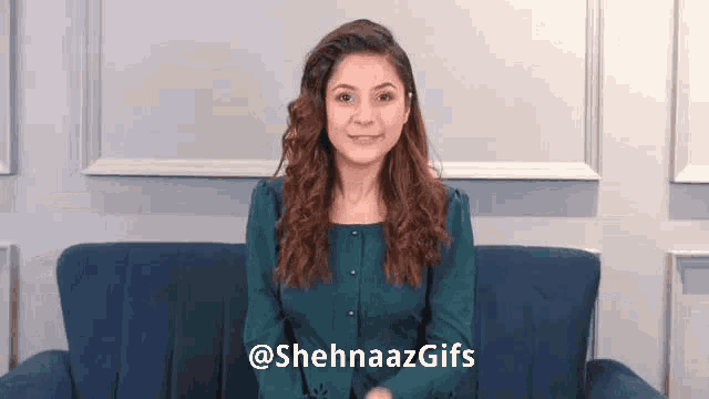 a woman in a green shirt is sitting on a blue couch and smiling