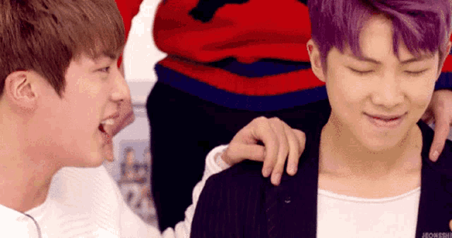 two young men with purple hair are laughing and one has his hand on the other 's shoulder .