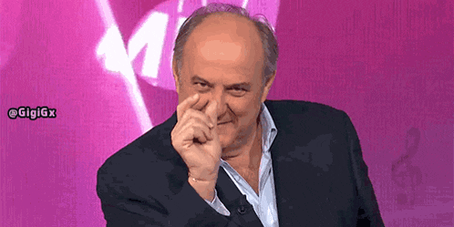 a man in a suit is covering his nose with his hand in front of a pink background