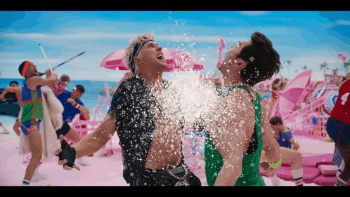 a man in a green tank top is being sprayed with water by another man in a black shirt