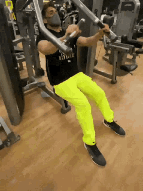 a man wearing a mask is working out on a machine in a gym .