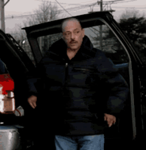a man in a black jacket is standing in front of a car with the word oh written on it