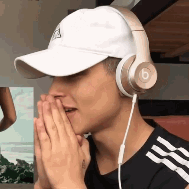 a man wearing headphones and a white hat has the letter b on the headphones