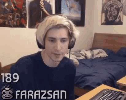 a young man wearing headphones is sitting at a desk in a bedroom .