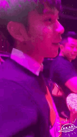 a man in a suit is sitting in front of a purple light