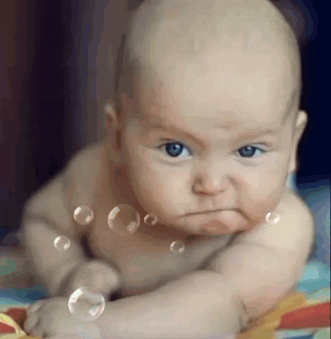 a baby is laying on a bed with soap bubbles coming out of his mouth