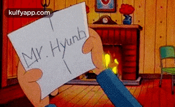 a person is holding a piece of paper with the name mr. hyunb written on it in front of a fireplace .