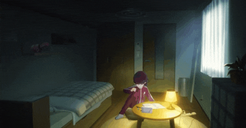 a person sits at a small table in a dark bedroom