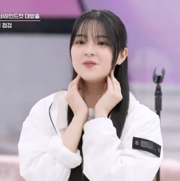 a young woman in a white jacket holds her hands to her chin
