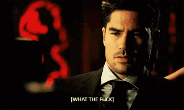 a man in a suit says what the fuck in a dark room