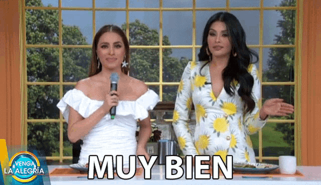 two women standing next to each other with the word muy bien written on the screen