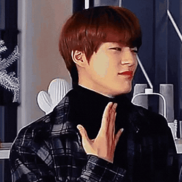 a young man with red hair and a black turtleneck is making a funny face .