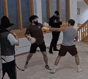 two men are boxing in a room with a man taking a picture of them
