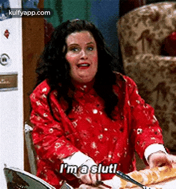 a woman is sitting at a table cutting a loaf of bread and saying `` i 'm a slut ! ''