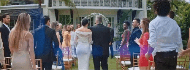 a bride and groom are walking down the aisle at their wedding while their wedding guests watch .