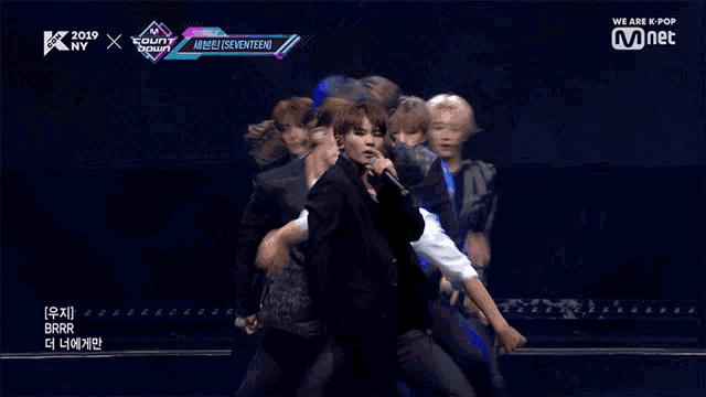 a group of men are performing on a stage with the words we are k pop on the bottom left