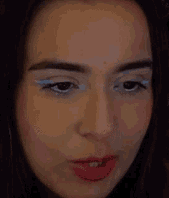 a close up of a woman 's face with red lips and white eyeliner .
