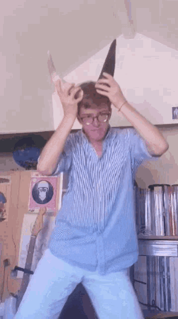 a man wearing glasses and a blue striped shirt is holding a cone in his hands
