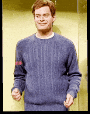 a man wearing a blue sweater is smiling and making a funny face
