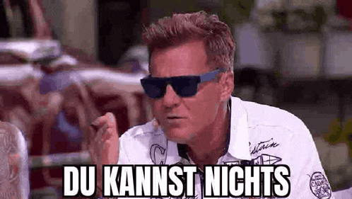 a man wearing sunglasses and a white shirt is making a funny face and says du kannst nichts .