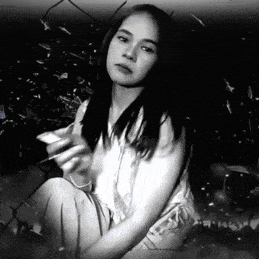 a black and white photo of a young woman holding a cell phone