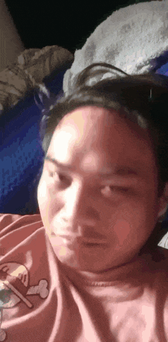 a man in a pink shirt with a bone on it is laying in bed