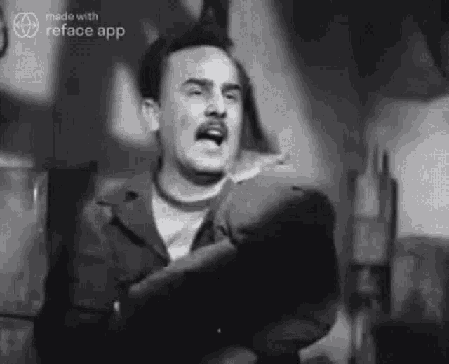 a black and white photo of a man with a mustache standing in a room .