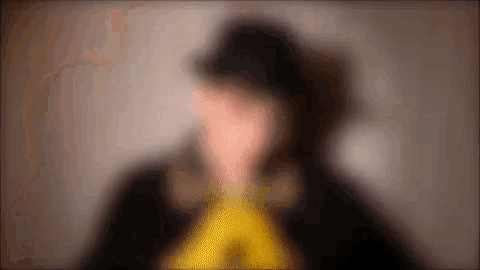 a blurry picture of a man wearing a black hat and a yellow scarf