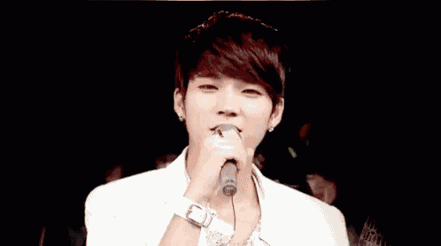 a young man is smiling while holding a microphone in front of him .