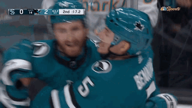 a hockey player with the number 5 on his jersey hugging another player