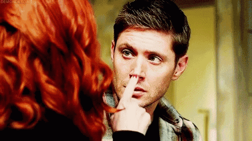 a man with red hair is being touched by a woman 's hand .