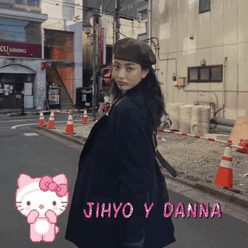 a girl in a black coat is standing in front of a building with the name jihyo y danna