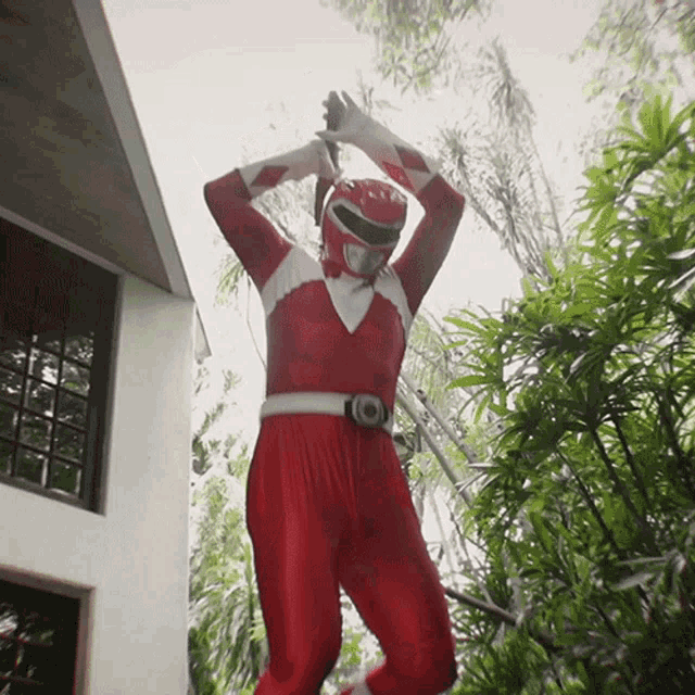 a man in a red power ranger costume stands in front of a building