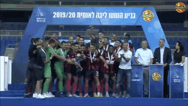 a group of soccer players standing in front of a banner that says ' 2019/20 ' on it