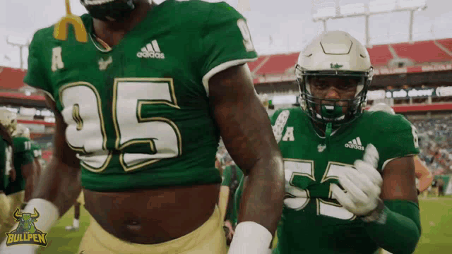 two football players wearing green jerseys with the number 55 on them