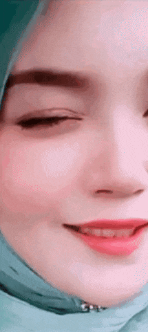 a close up of a woman 's face wearing a hijab and smiling .