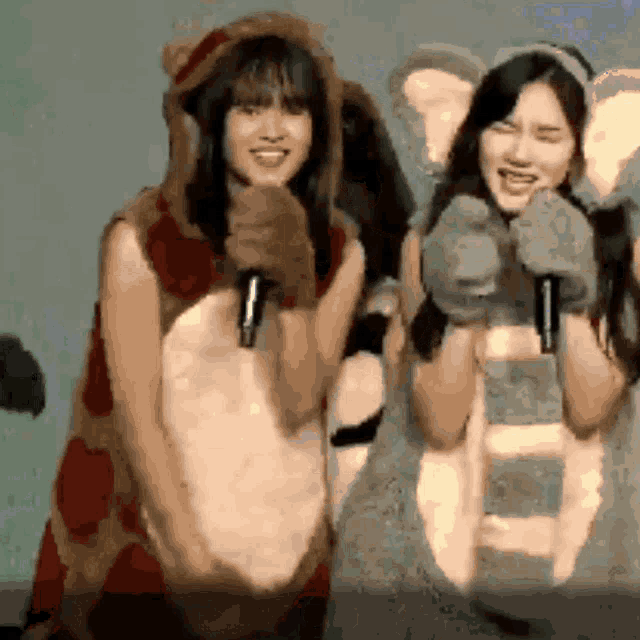 two girls dressed in animal costumes are holding microphones and smiling