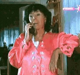 a woman in a pink jacket is talking on a cellphone