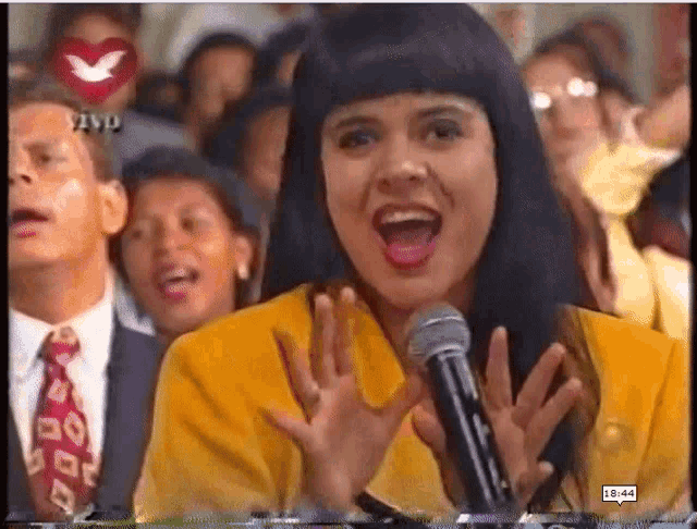 a woman singing into a microphone with the time of 15:44 on the bottom