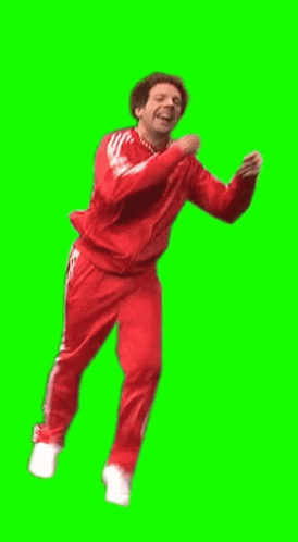 a man in a red adidas tracksuit is dancing against a green screen .