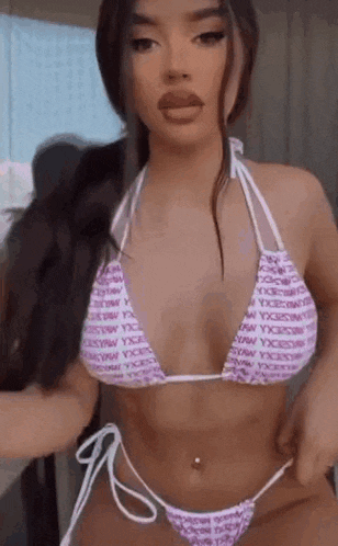 a woman in a pink bikini is standing in a room .