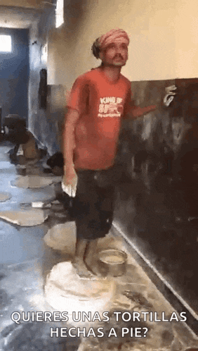 a man in a red shirt is standing in front of a wall holding a paint brush .