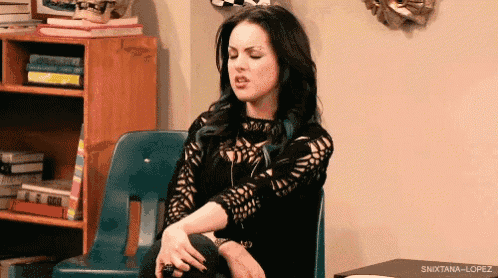 a woman is sitting in a chair with her hands on her knees and making a funny face .