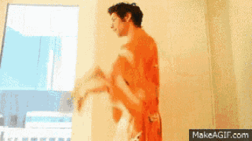 a man in a bathrobe is dancing in front of a window on makeagif.com