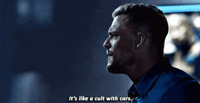 a man in a blue suit is talking to another man in a dark room .