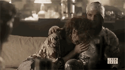 a man and a woman are sitting on a couch hugging .