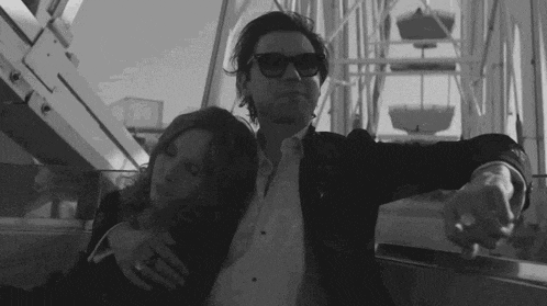 a man and a woman are riding a ferris wheel .